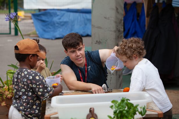 Male educator playing outside with young children