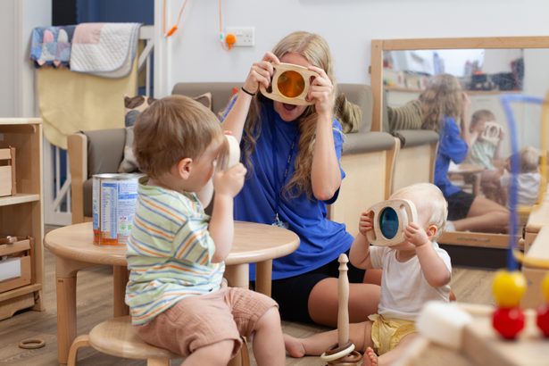 Nursery worker playing with young children