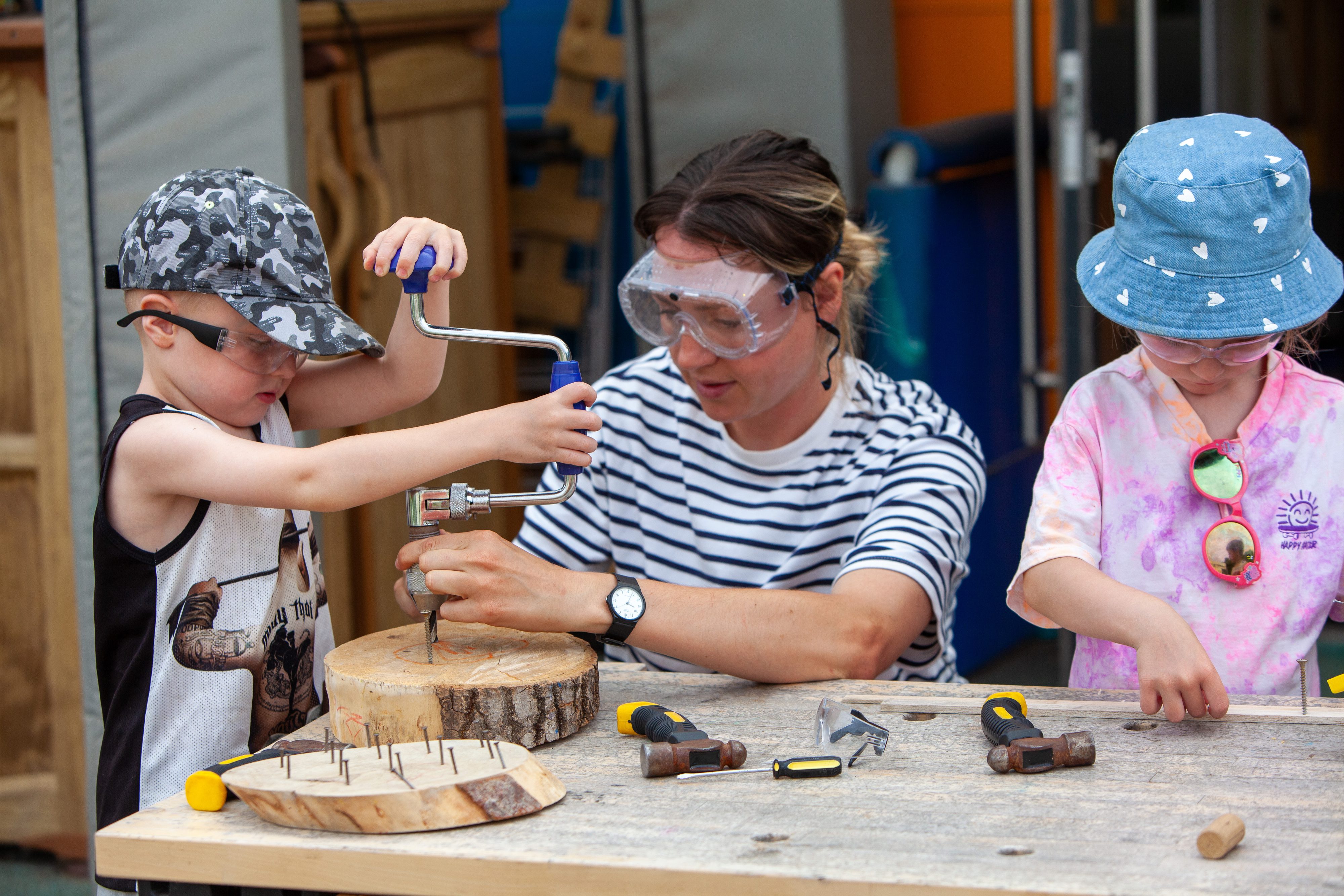 Young children and educator drilling wood